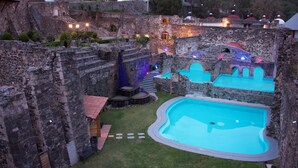 A courtyard with a swimming pool, stone walls, and a staircase leading to a higher level. - Hacienda Santa Maria Regla (San Miguel Regla)