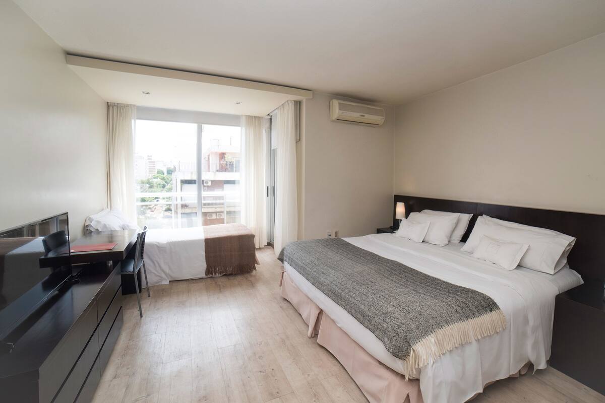 A modern hotel room with a bed, a desk, and a TV.