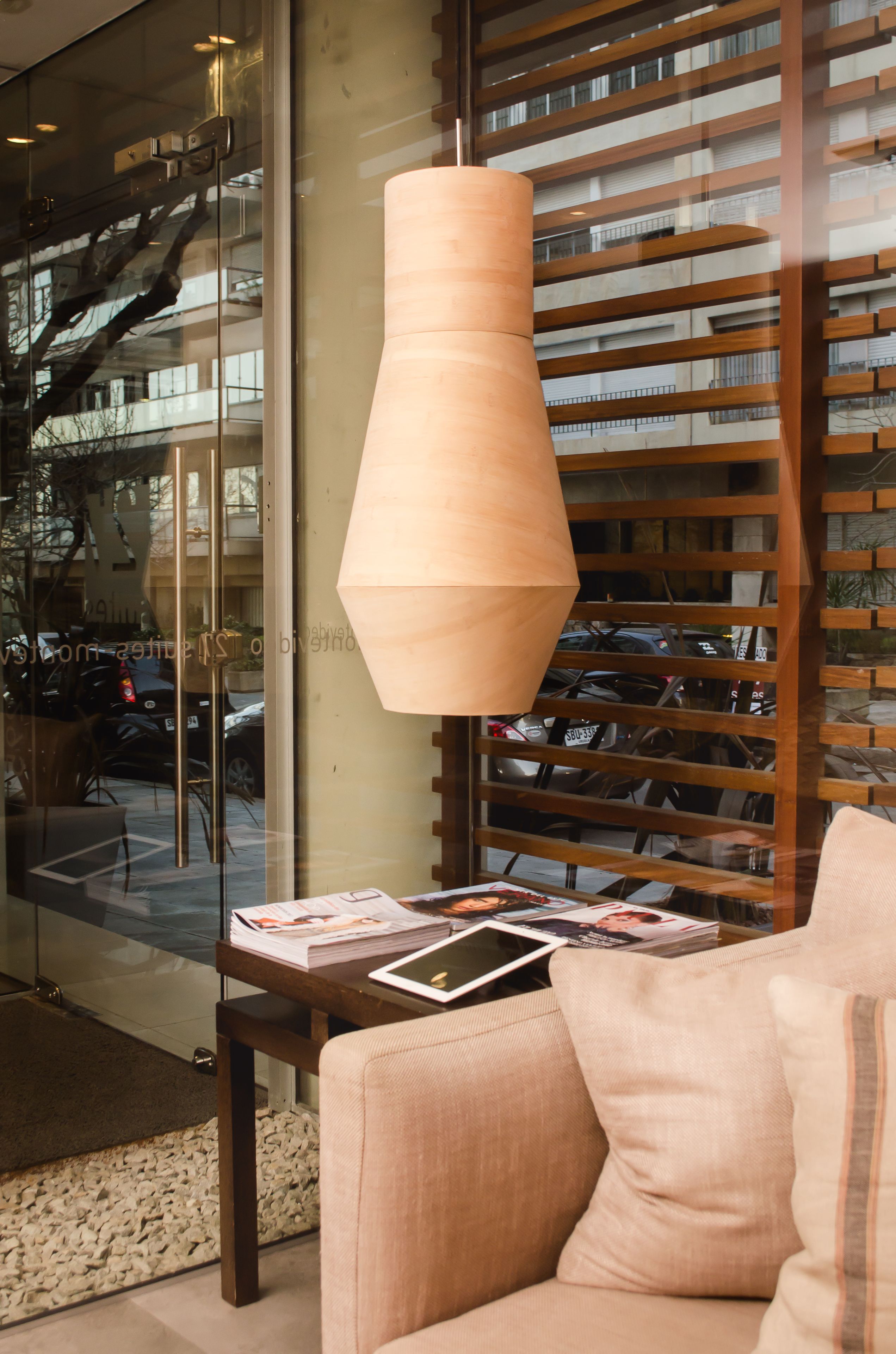 A modern interior with a sofa, a table with magazines, and a hanging pendant light.