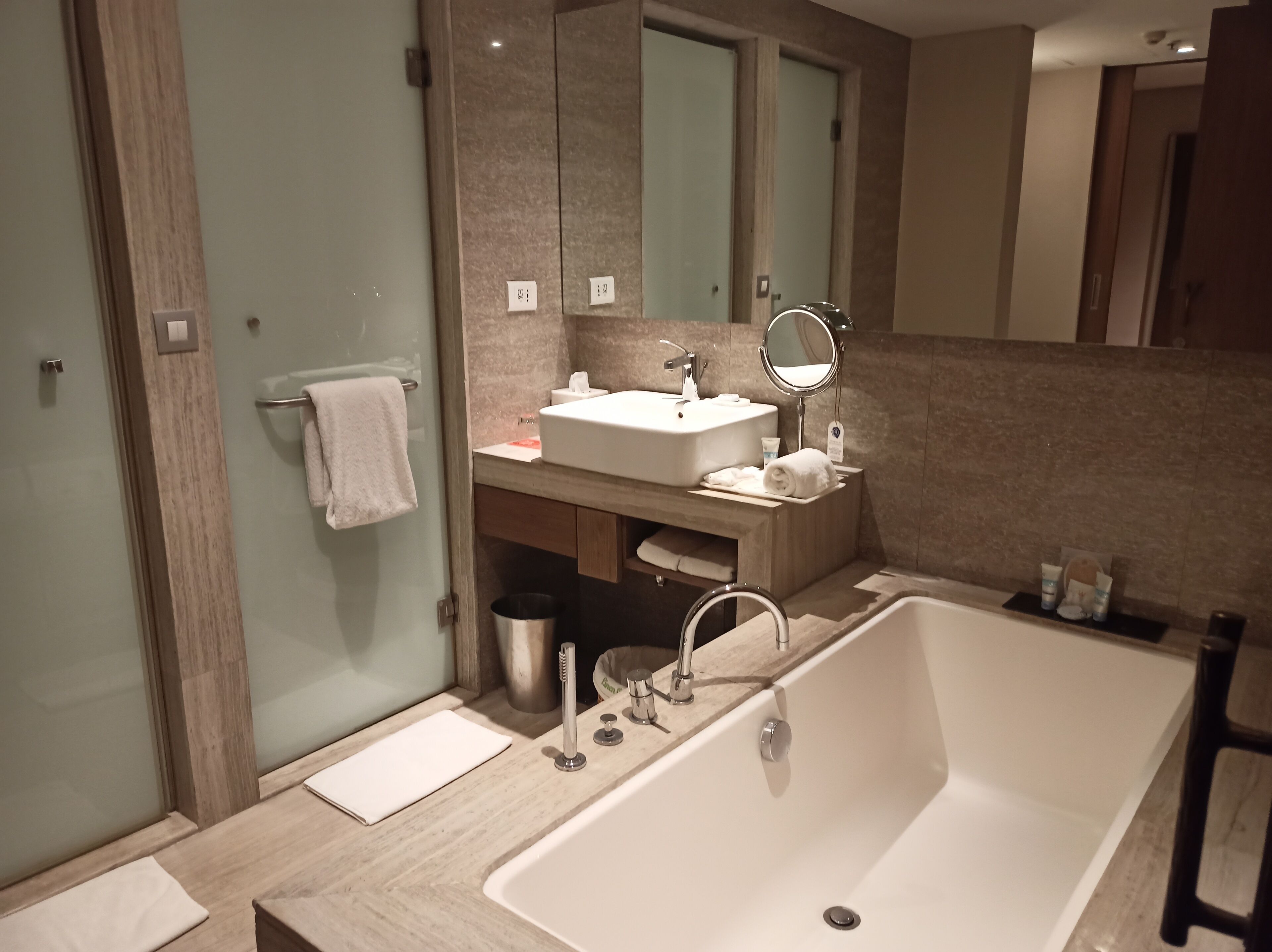 Un baño moderno con una bañera grande, un lavamanos con espejo y un perchero para toallas.