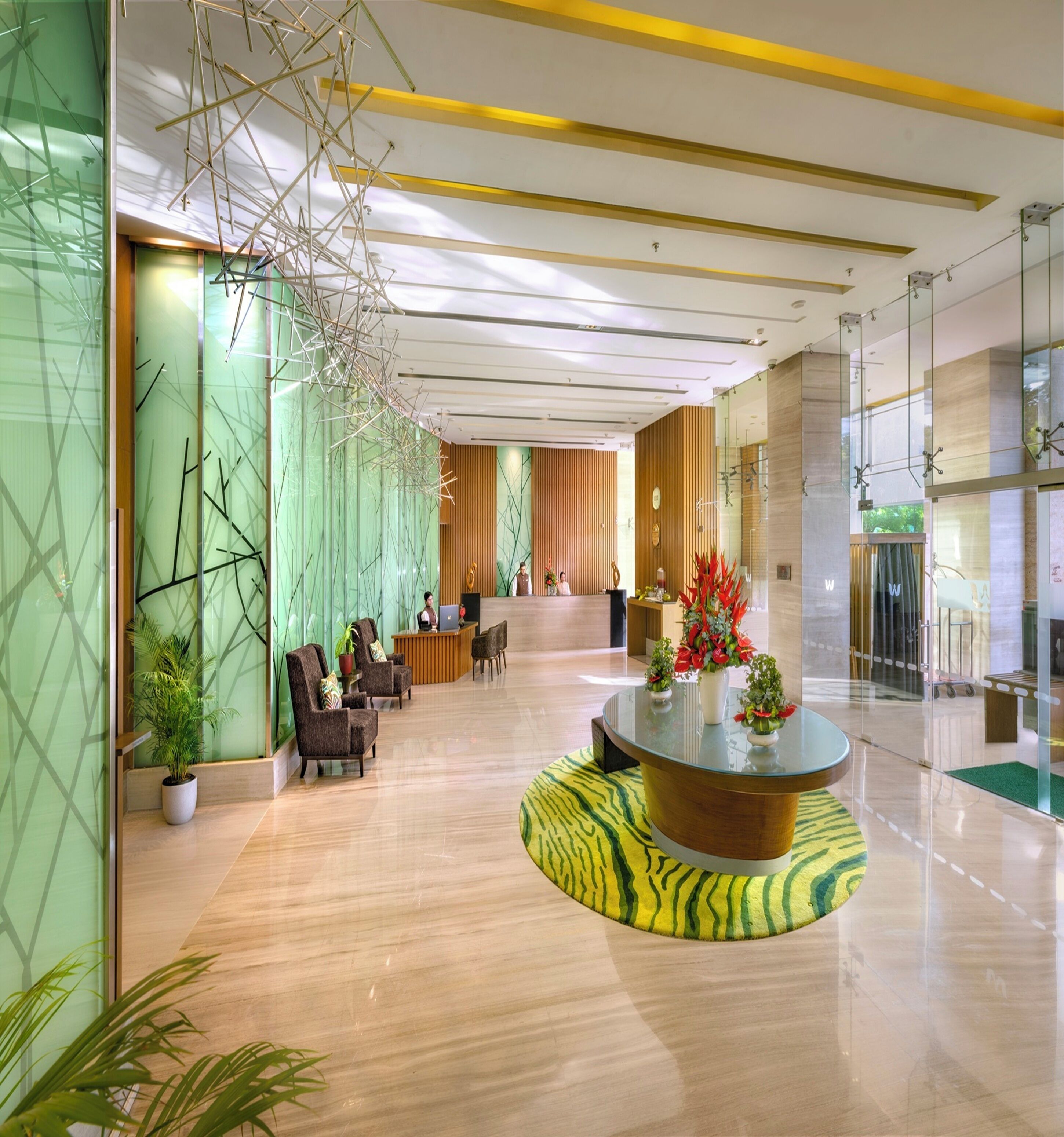 A modern lobby with a reception desk, seating area, and a decorative glass table with plants.