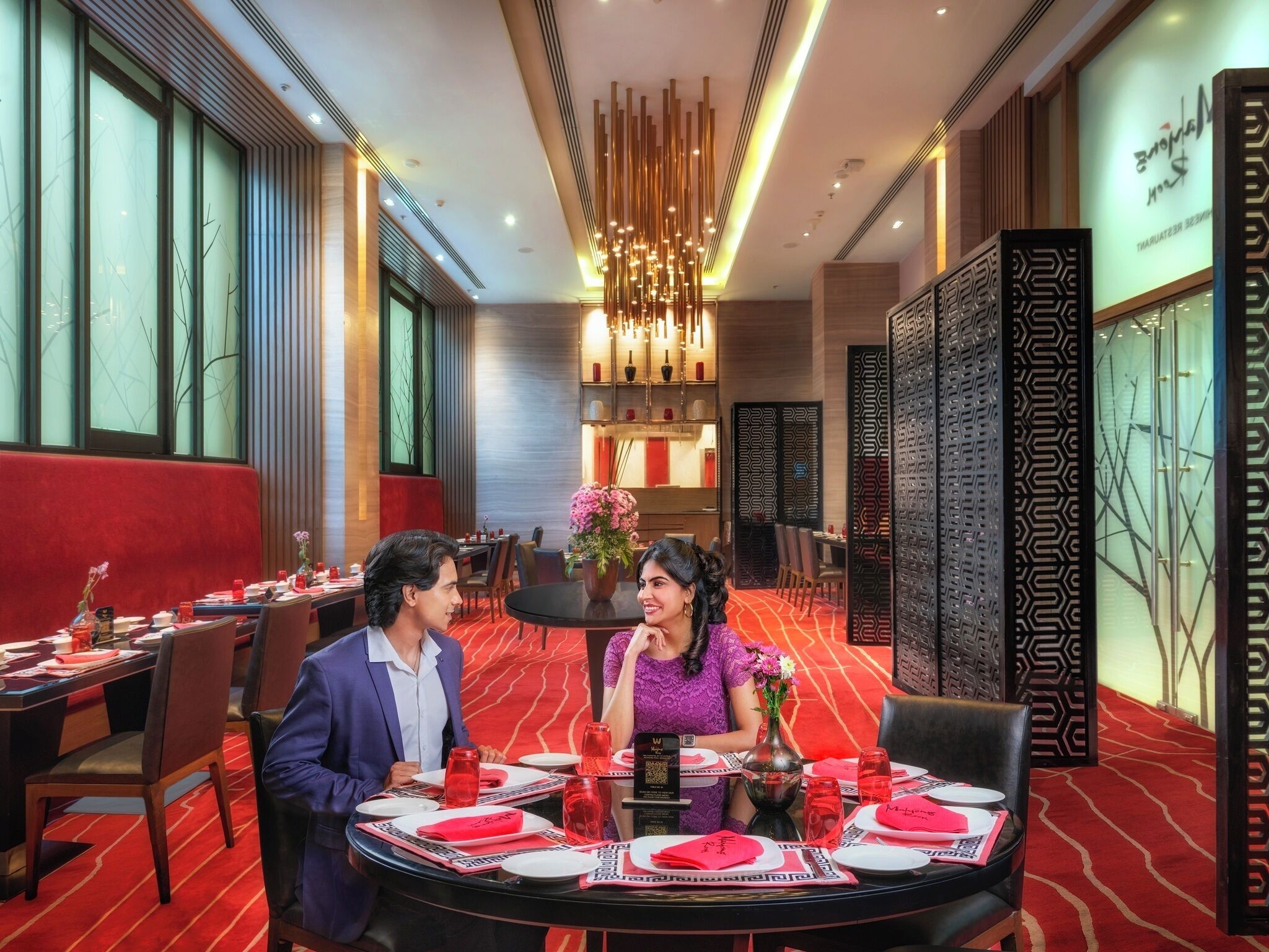 A restaurant with round tables, red carpets, and modern decor.