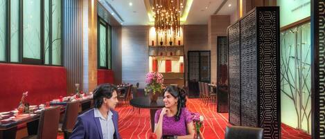 A restaurant with round tables, red carpets, and modern decor.