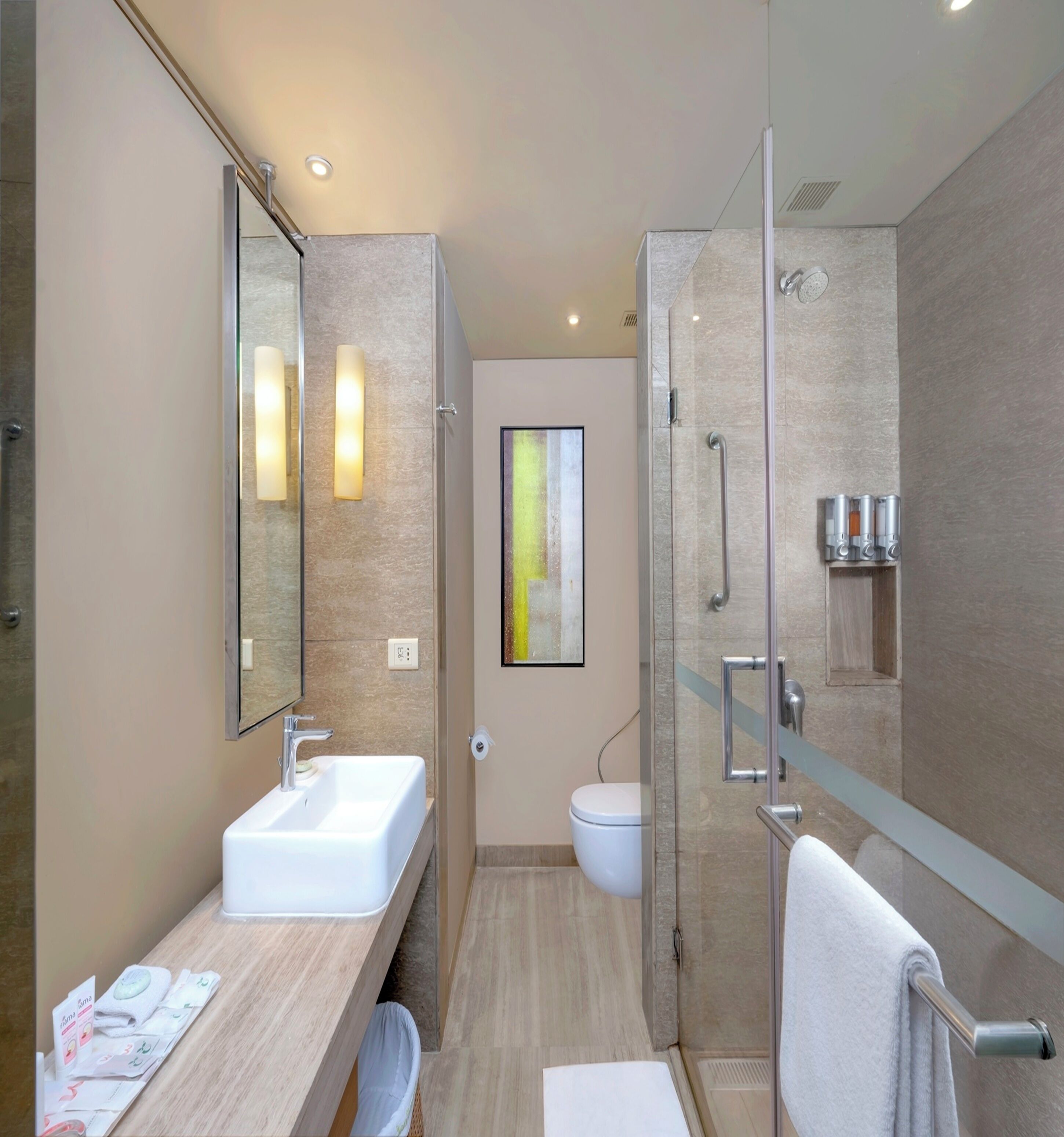 Un baño moderno con cabina de ducha de vidrio, un lavabo blanco y un espejo grande.