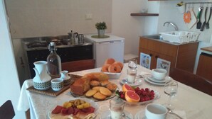 A breakfast table set with various foods, a coffee pot, and a small plant.