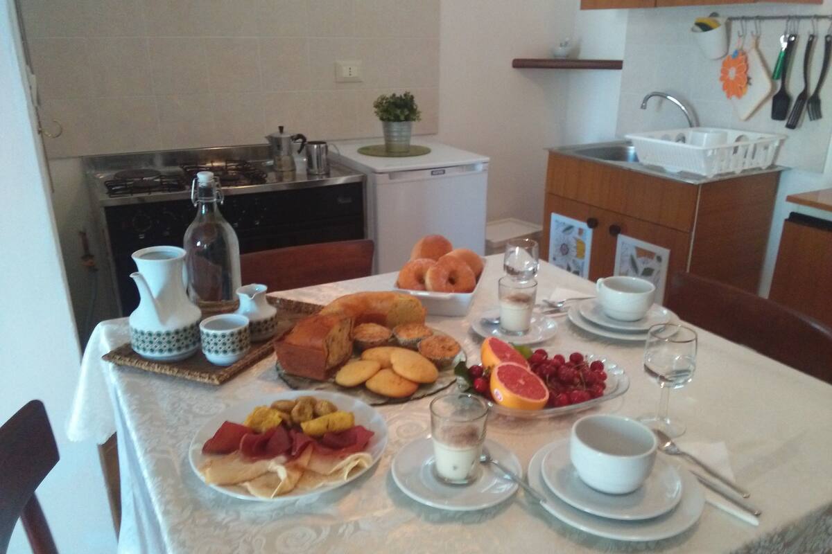 A breakfast table set with various foods, a coffee pot, and a small plant.