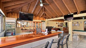 Uma área de bar com vigas de madeira, balcão e assentos.