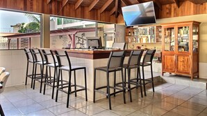 Zona de bar com teto de madeira, uma TV na parede e balcão com banquetas.