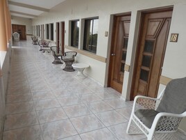 A corridor with tiled flooring, wicker chairs, and a white table.
