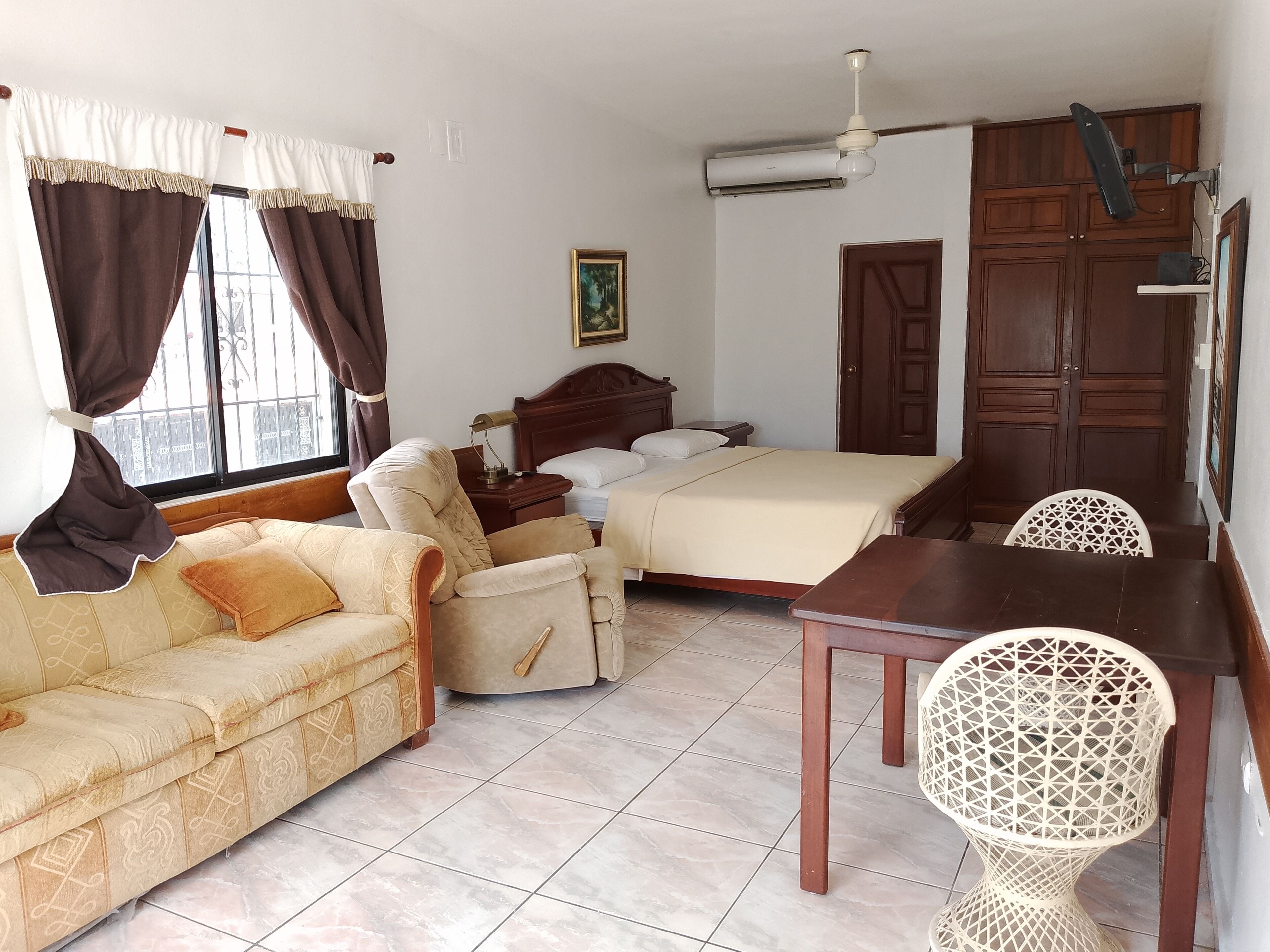 A hotel room with a bed, a sofa, a dining table, and a chair.