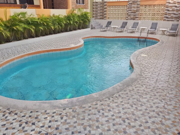 Alberca al aire libre y camastros 