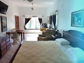 A hotel room with a bed, a desk, a chair, a sofa, and a television.