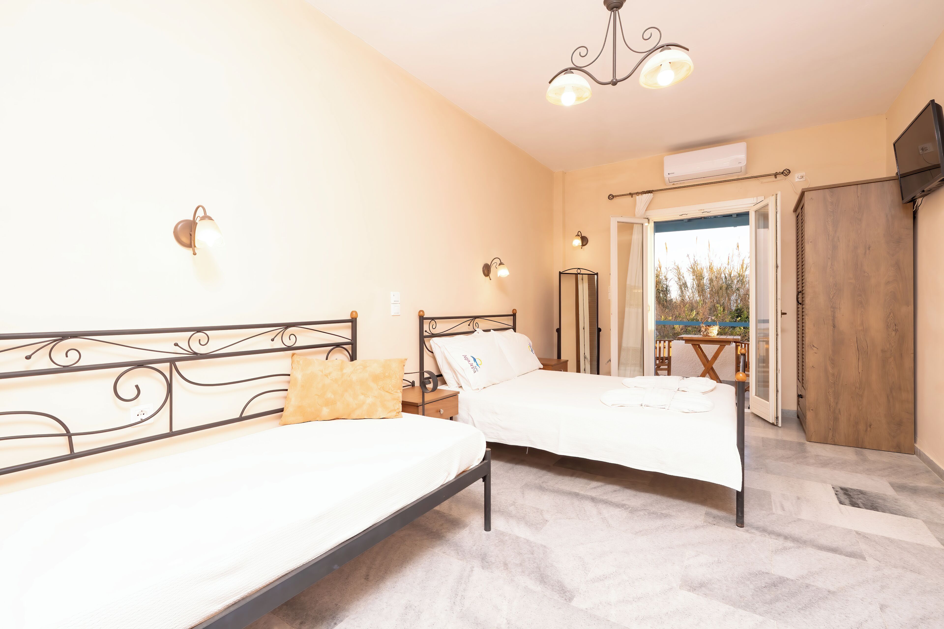 A bedroom with two beds, a chandelier, an air conditioner, and a view of the outdoors.