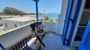 En balkon med et bord dækket til morgenmad, med udsigt over kysten.