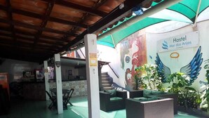 Interior de un hostal con suelo de baldosas, zonas de estar, una escalera y un mural en la pared.