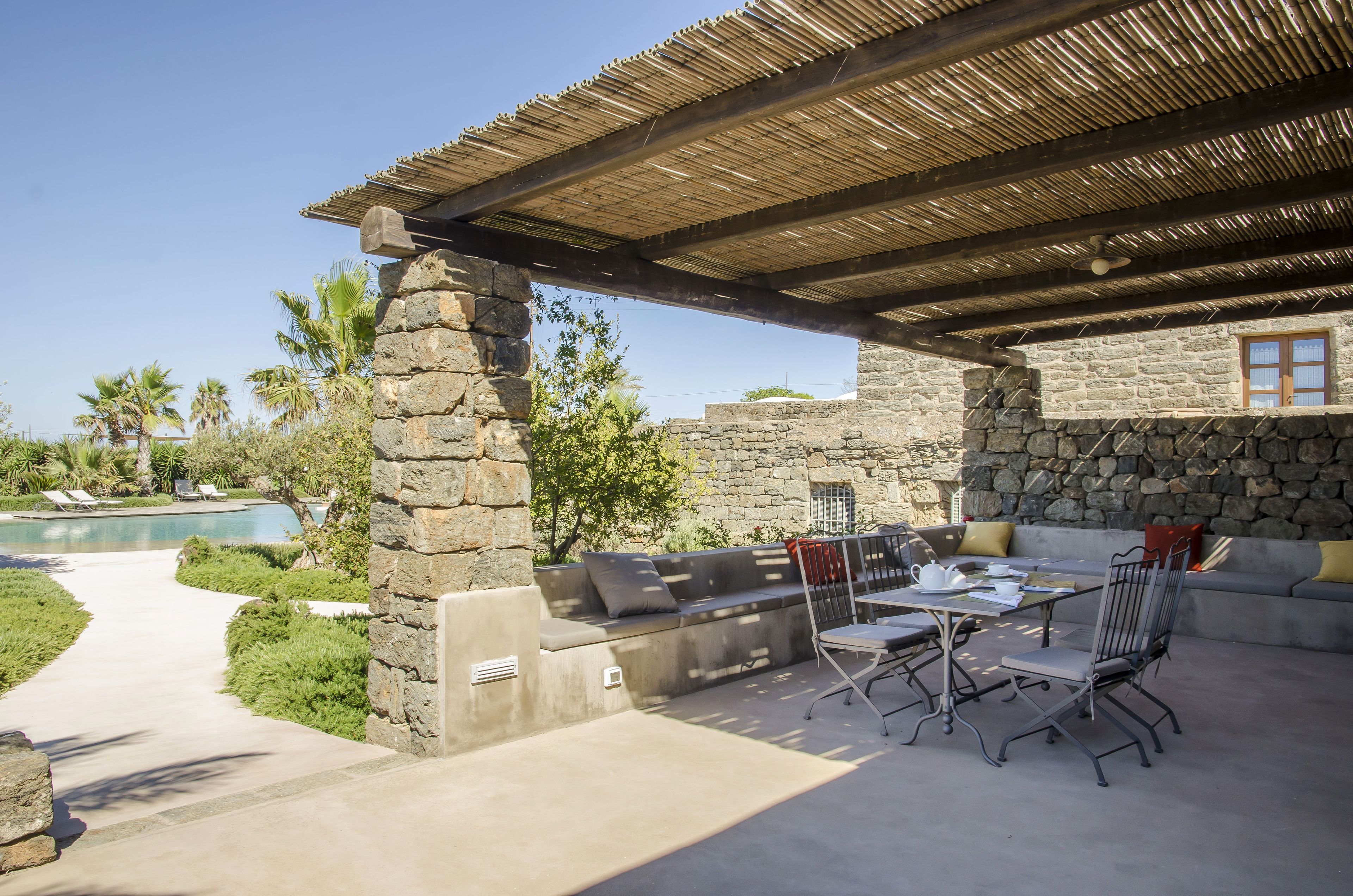 An outdoor patio with stone walls, a pool, and a covered seating area.