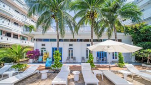 A hotel courtyard with sun loungers, a pool, and palm trees. - Blue Carina Hotel (Wichit)