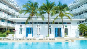 Un hôtel doté d’une piscine, de bâtiments blancs, de portes bleues et de palmiers.