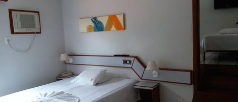 Una habitación de hotel con cama, mesita de noche, lámpara y un cuadro en la pared.