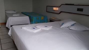 Habitación de hotel con dos camas, cada una con toallas y almohadas bien ordenadas.