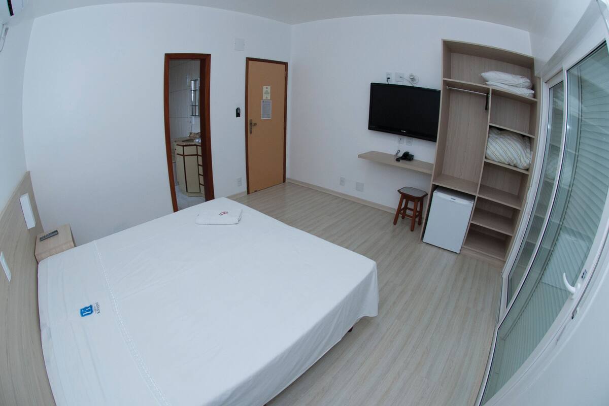 A room with a bed, a TV, a wardrobe, and a door.