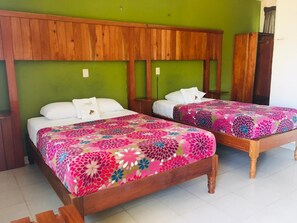 A room with two wooden beds, green walls, and a wooden headboard. - Hotel Maya Balam (Calakmul)