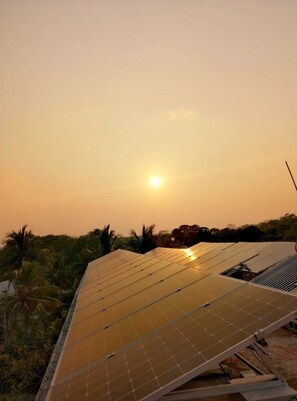 Solar panels on a rooftop with a sunset in the background. - Hotel Maya Balam (Calakmul)