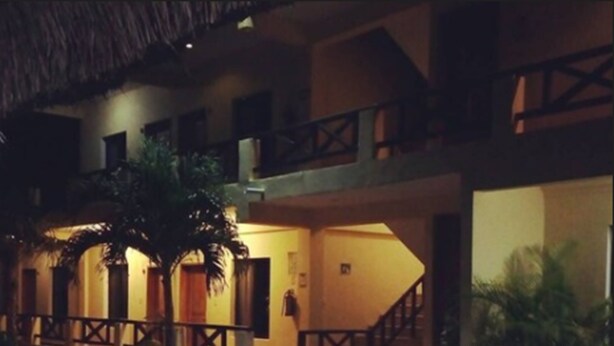 A multi-story building with a thatched roof, a central courtyard, and a staircase leading to the upper levels. - Hotel Maya Balam (Calakmul)