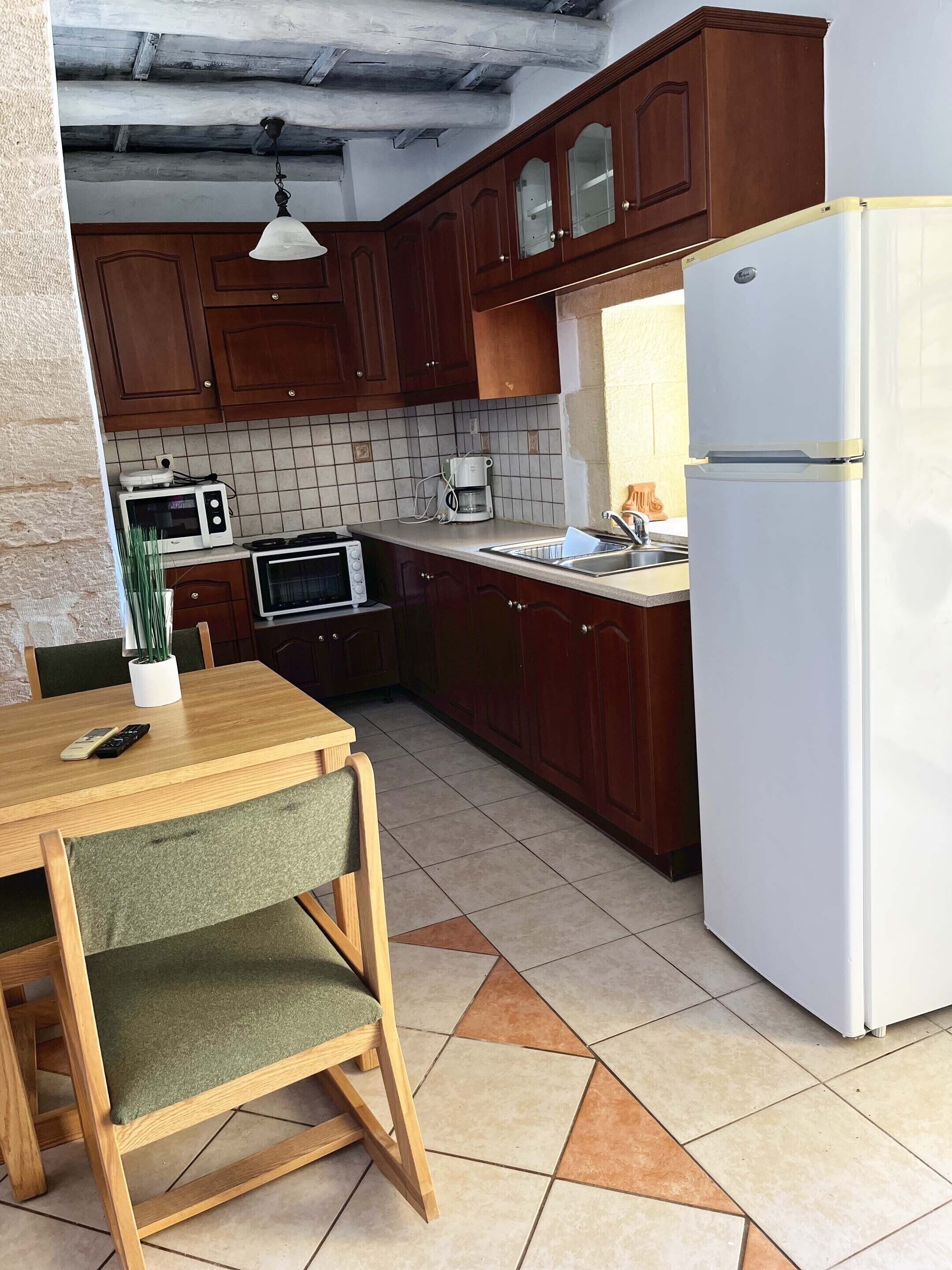 A kitchen with wooden cabinets, a white refrigerator, a microwave, a coffee maker, and a dining table with chairs.