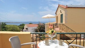 A balcony with a table set for two, overlooking a scenic view of the sea. - Skandalis Traditional Suites (Chania)
