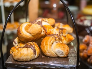 A display of croissants with chocolate drizzle, arranged on a wooden stand. - Alameda Paradiso Hotel (Gramado)