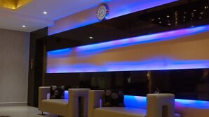 A modern lounge area with two sofas and a wall-mounted clock. - Buhari Royale Boutique Hotel (Chennai)