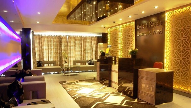 A modern hotel lobby with a reception desk, seating area, and decorative wall patterns. - Buhari Royale Boutique Hotel (Chennai)