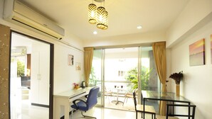 A modern living room with a glass dining table, blue and black chairs, a glass coffee table, and a ceiling light fixture. - Baan Sabai Rama IV (Bangkok)