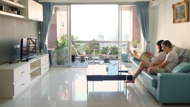 A modern living room with a sofa, a TV, and a balcony with plants. - Baan Sabai Rama IV (Bangkok)