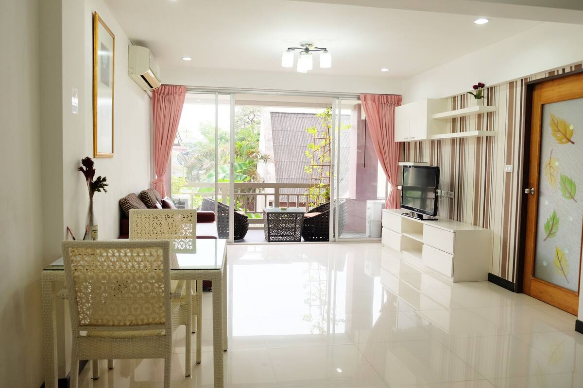 A modern living room with a dining area, a TV, and a sliding glass door to the outside.