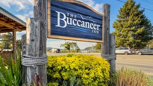 A wooden sign for The Buccaneer Inn with a clear view of the surrounding landscape and a road in the background. - Buccaneer Inn (Nanaimo)