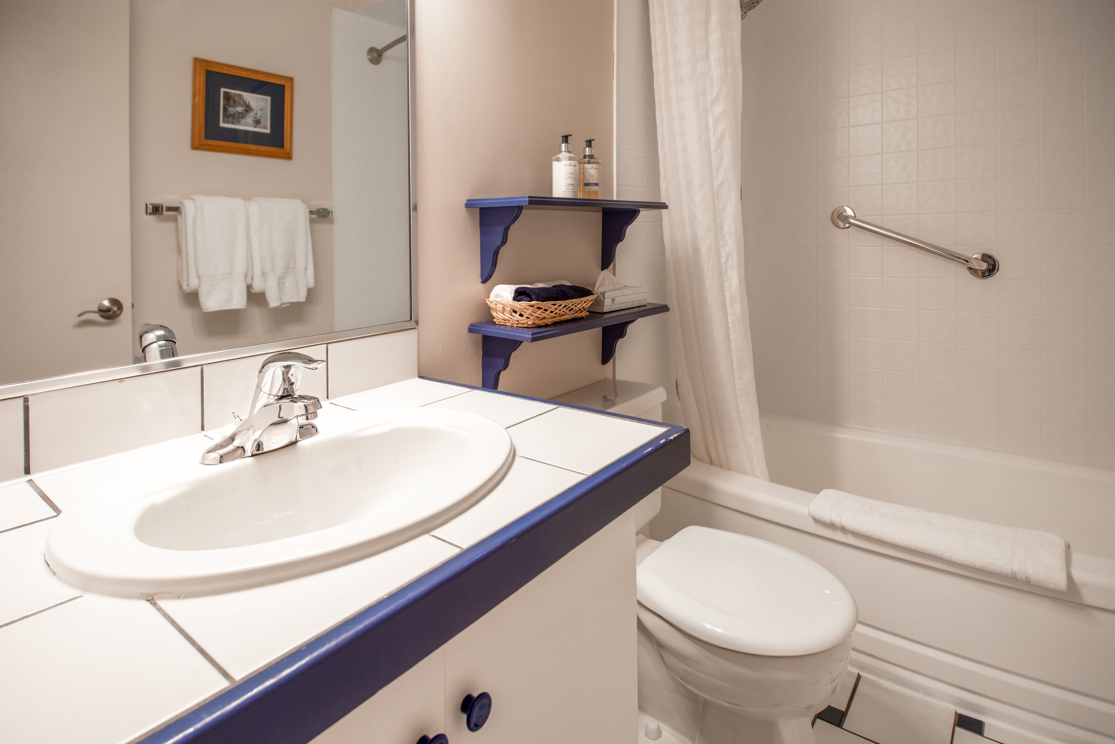 Un baño con lavamanos blanco, inodoro, cortina de ducha y toallero.