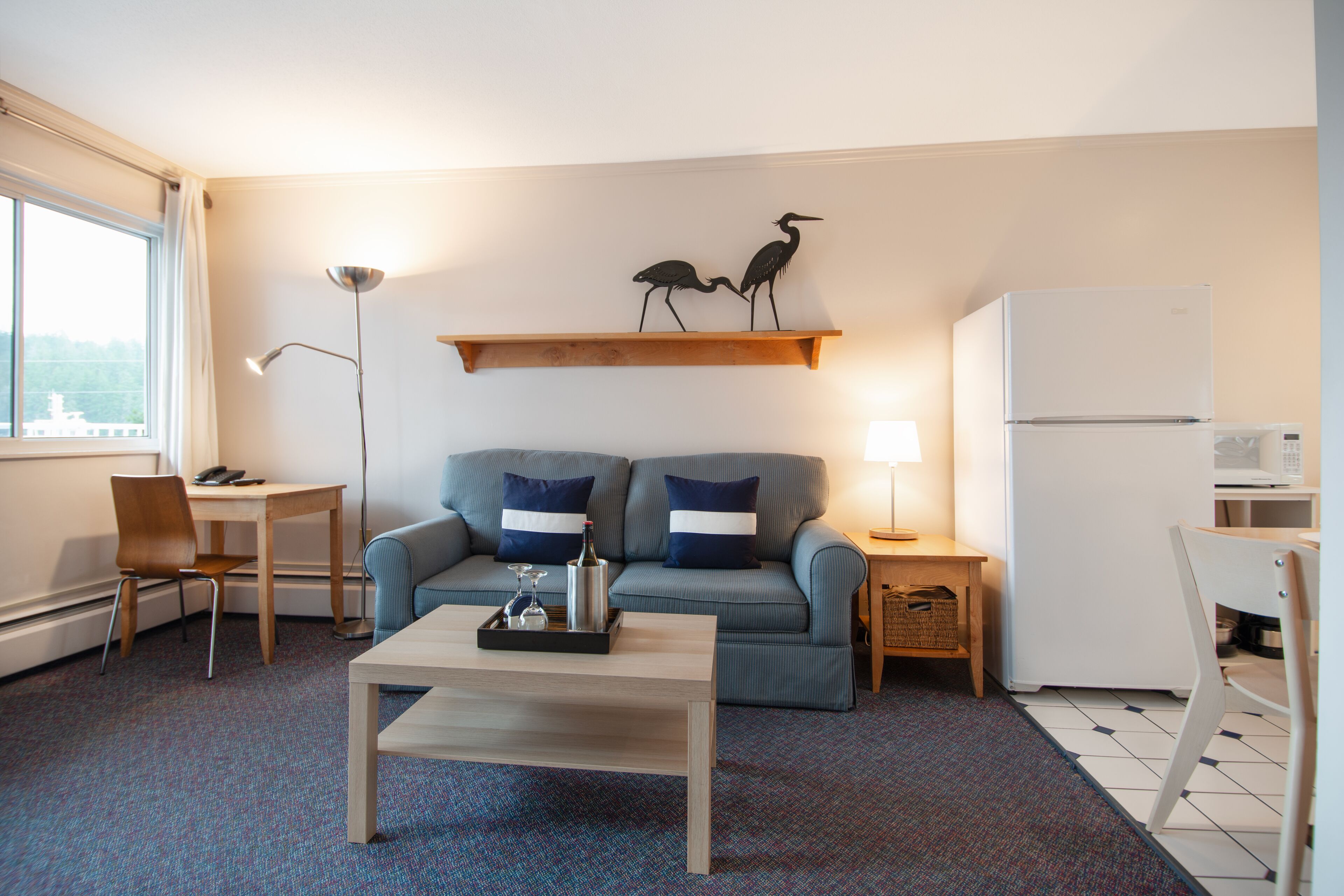 A compact living space with a sofa, a coffee table, a dining table, and a refrigerator.