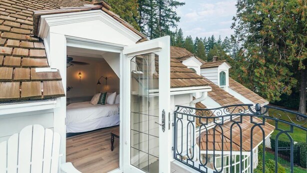 Una camera da letto mansardata accogliente con un letto, una scrivania piccola e una finestra che si affaccia su un giardino.