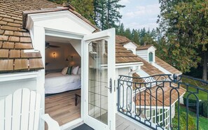 A cozy attic bedroom with a bed, a small desk, and a window overlooking a garden. - Rowena's Inn On The River (Harrison Mills)
