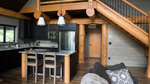 Una cucina moderna con isola centrale, sedie di legno e una scala con ringhiera in legno.