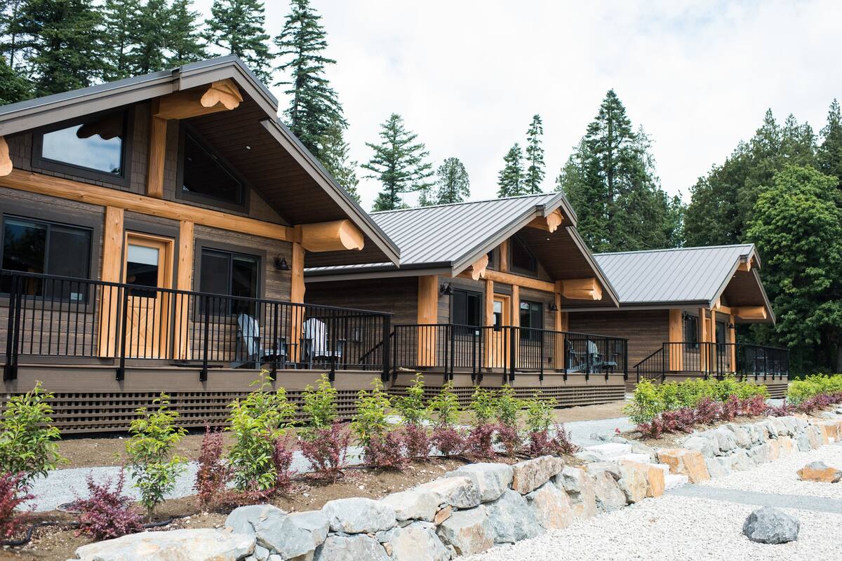 A modern lodge with a wooden exterior, large windows, and a stone pathway leading to the entrance.