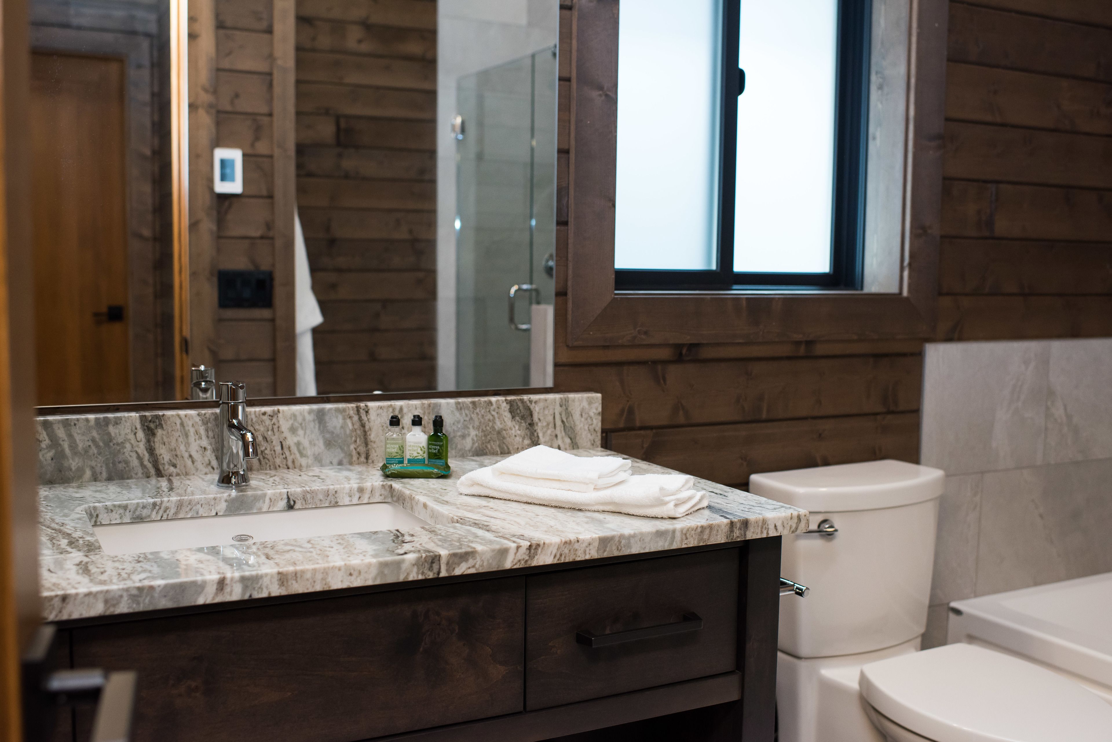 A bathroom with a marble sink, a toilet, and a window.