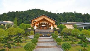 A large building with a prominent entrance, surrounded by well-maintained gardens and trees. - Tianmushan Hotspring Hotel (Yichun)