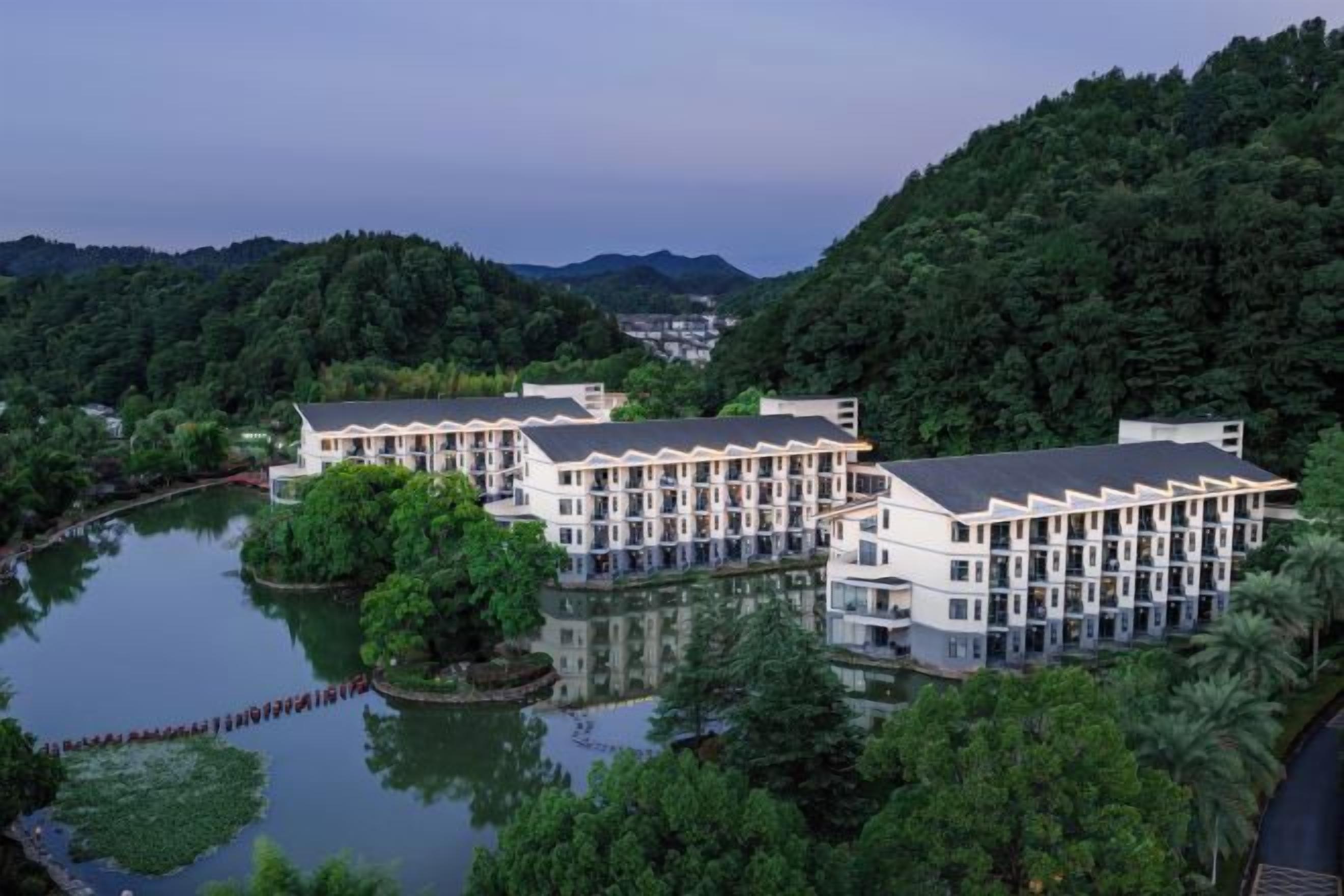 Un hotel con varias edificaciones, un lago y vegetación circundante.