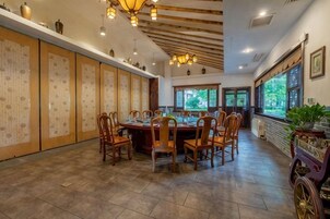 A traditional dining room with a long table, chairs, and decorative elements.