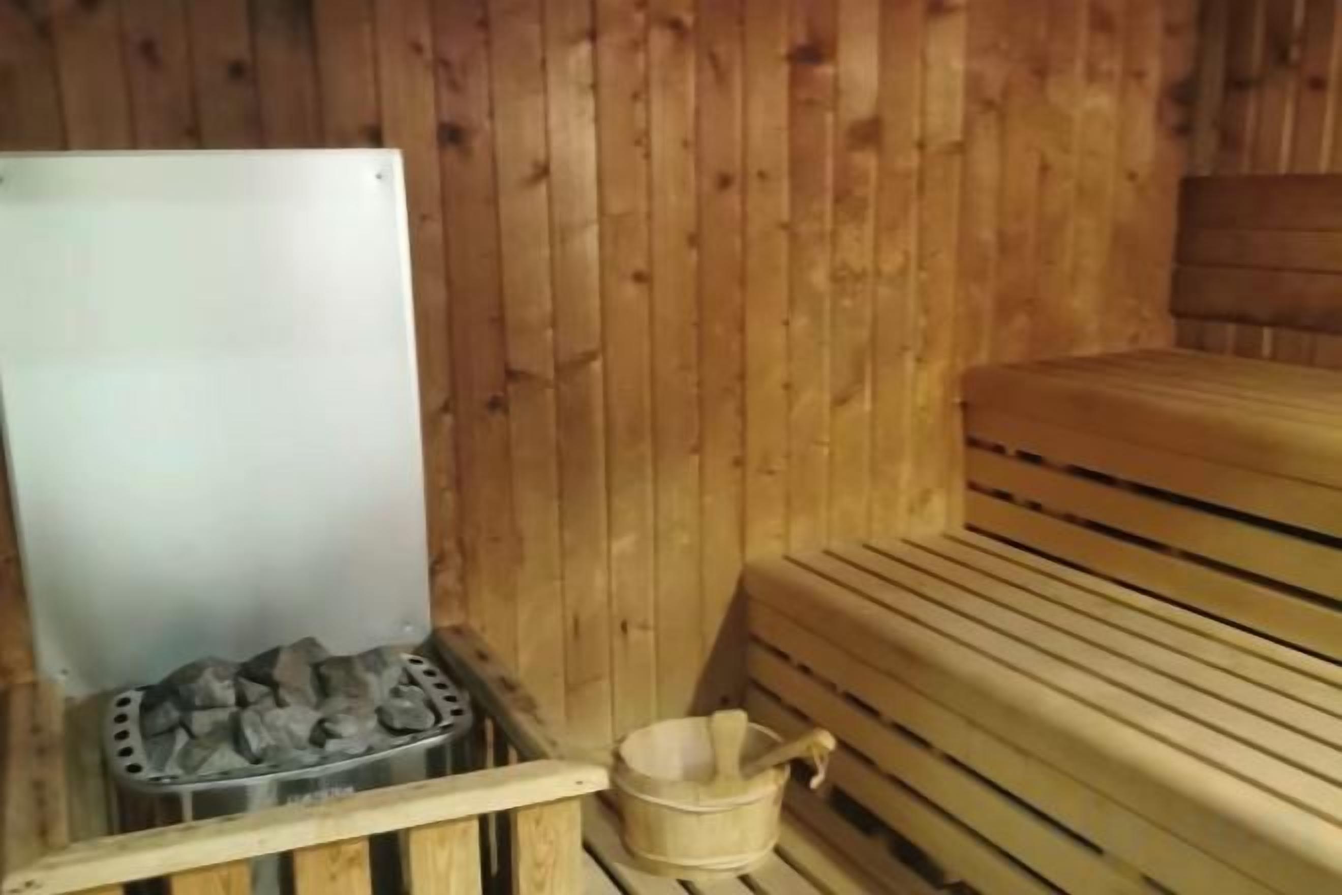 Een houten sauna met banken en een metalen bak voor stenen.