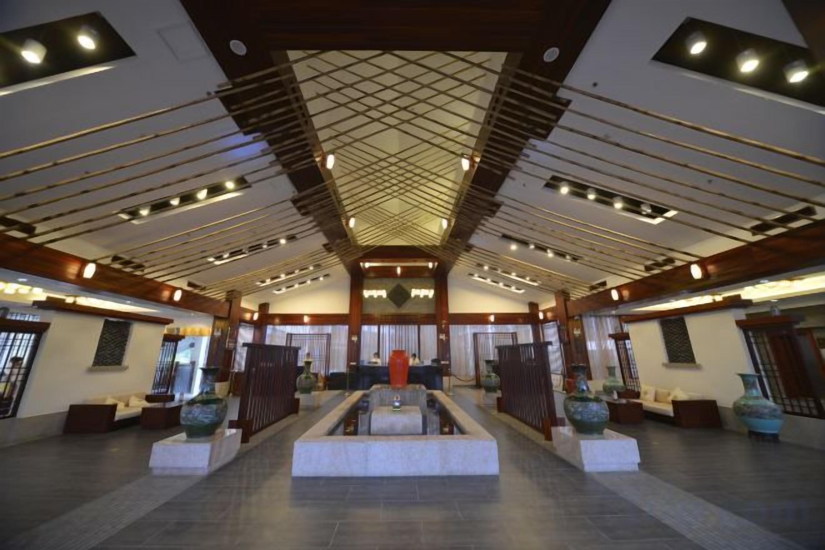 A spacious lobby with a high ceiling, a central fountain, and a reception desk.