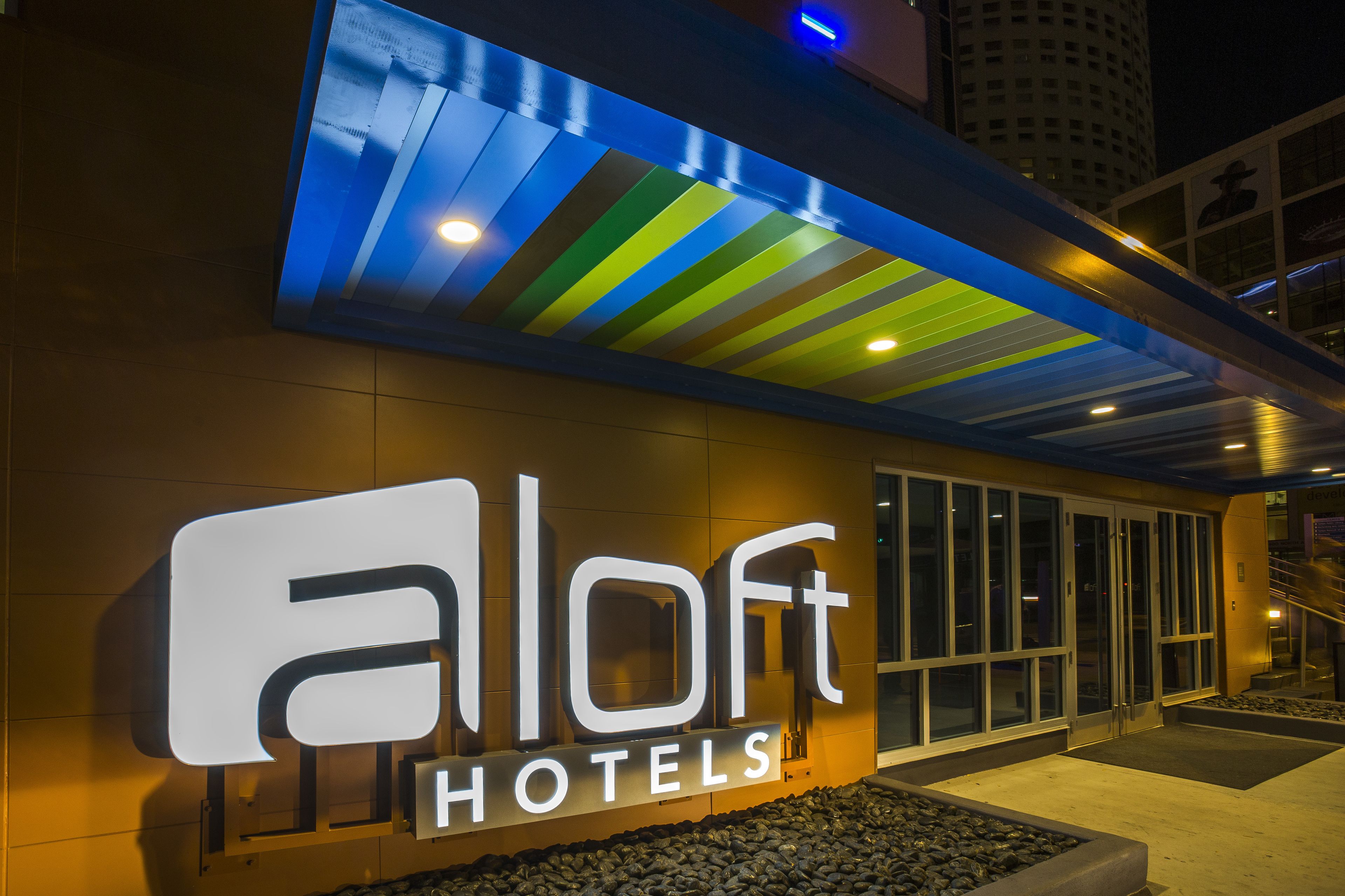 A hotel entrance with a modern sign and a covered walkway.